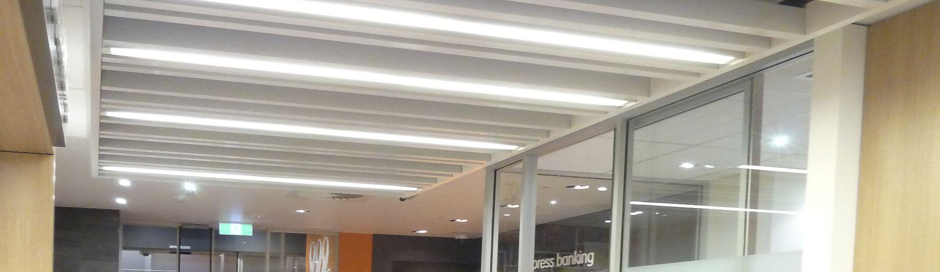 Decorative use of ALUCLICK aluminium beams with integrated lighting in retail bank